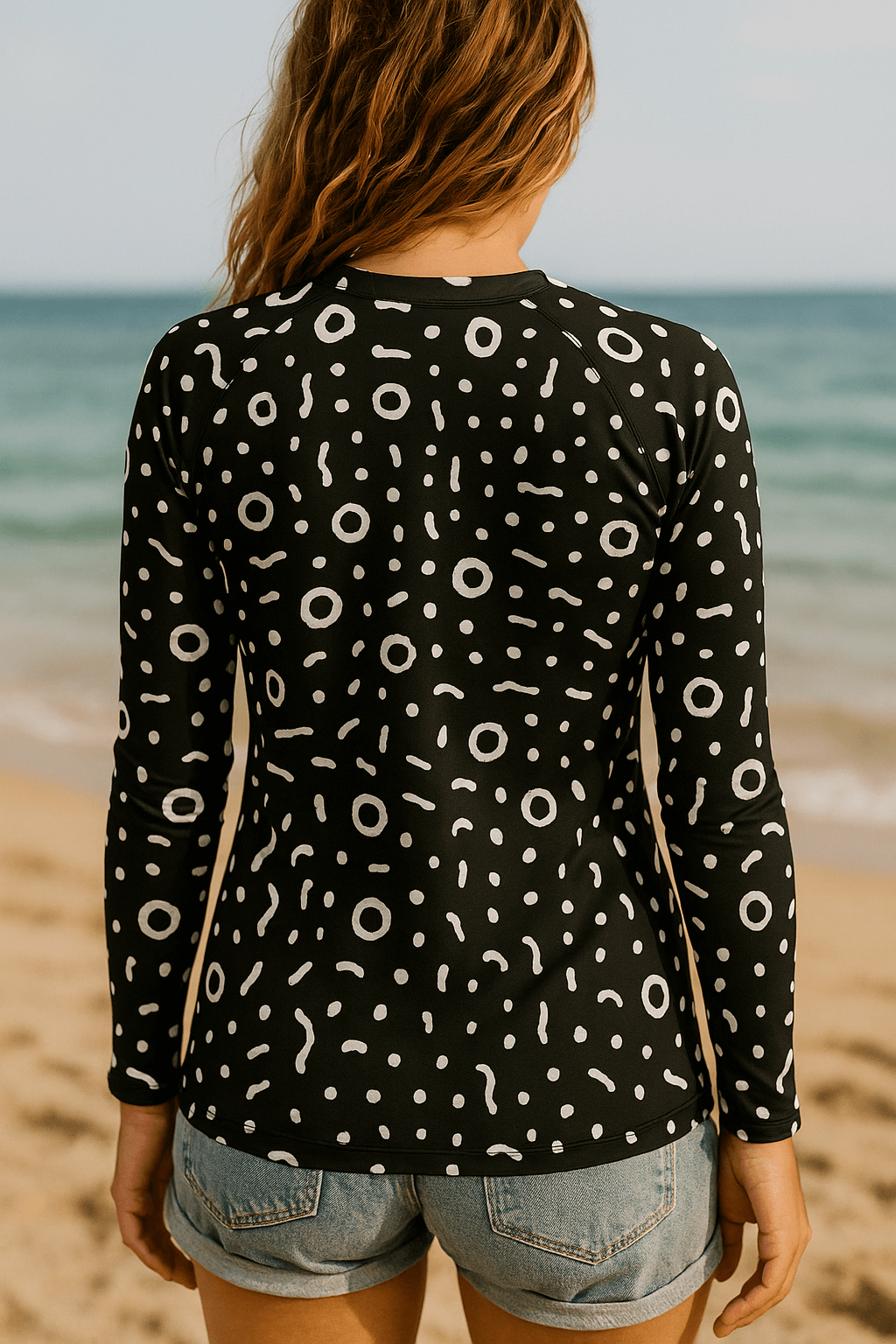 Woman wearing a black and white patterned rash guard on a beach