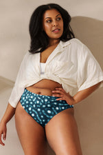 Load image into Gallery viewer, Woman wearing a white shirt over a white top and blue polka dot shorts against a beige background
