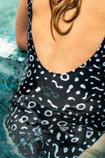 Load image into Gallery viewer, Person wearing a black swimsuit with white pattern in a pool
